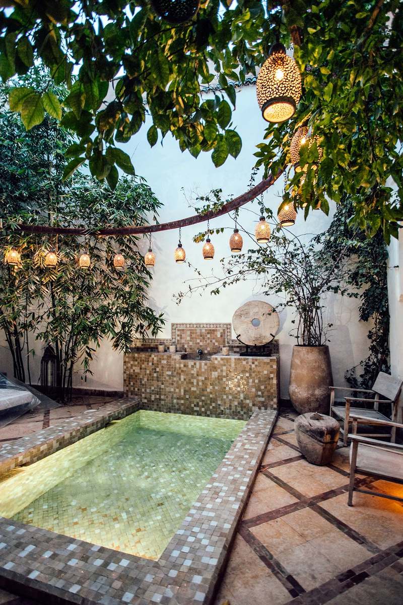 Lantern-lit mosaic pool nestled in a lush courtyard
