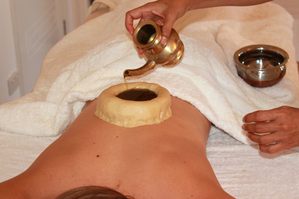 Warm oil poured for a Kati Basti back treatment