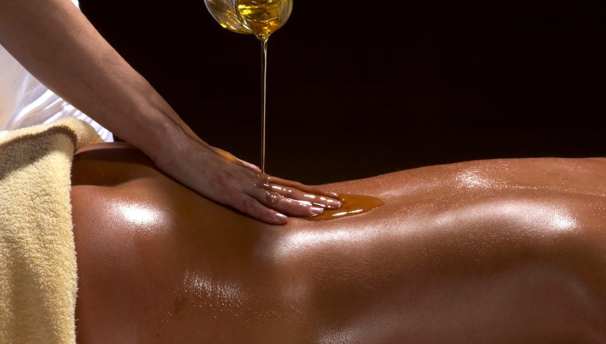 Warm oil poured over the back during a massage
