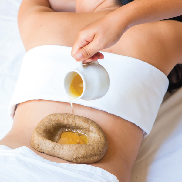 Therapist performing a Kati Basti lower back treatment