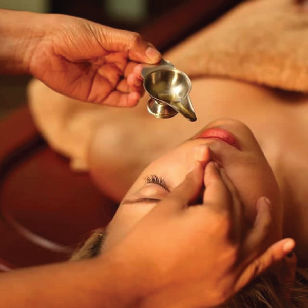 Therapist administering a Nasya nasal therapy