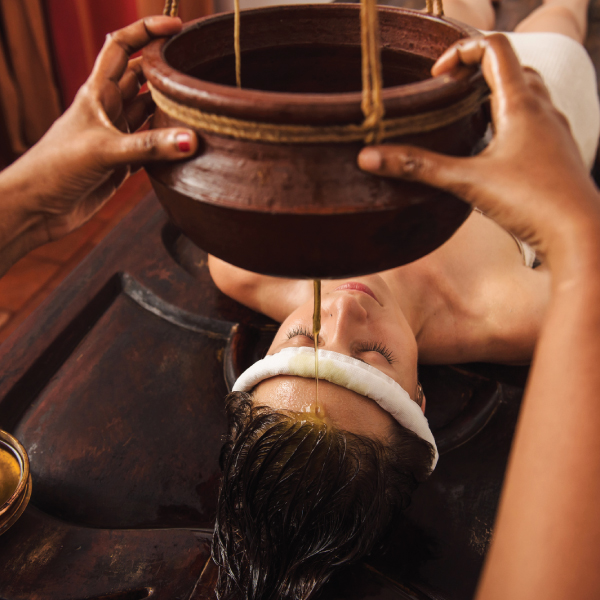 Guest receiving a Shirodhara warm oil pour treatment